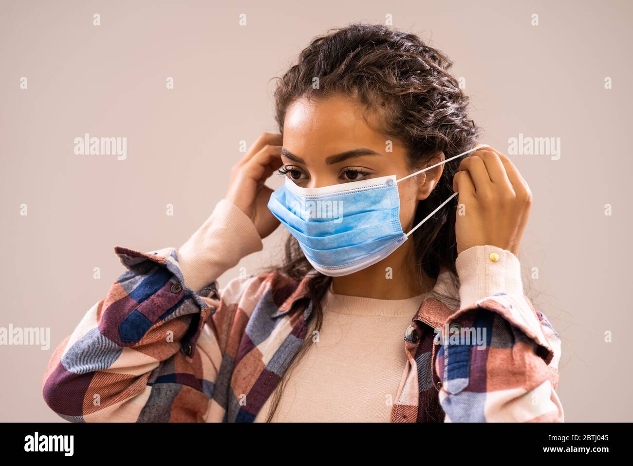 Studio shot portrait of beautiful african-american ethnicity woman who is putting protective mask. Stock Photo