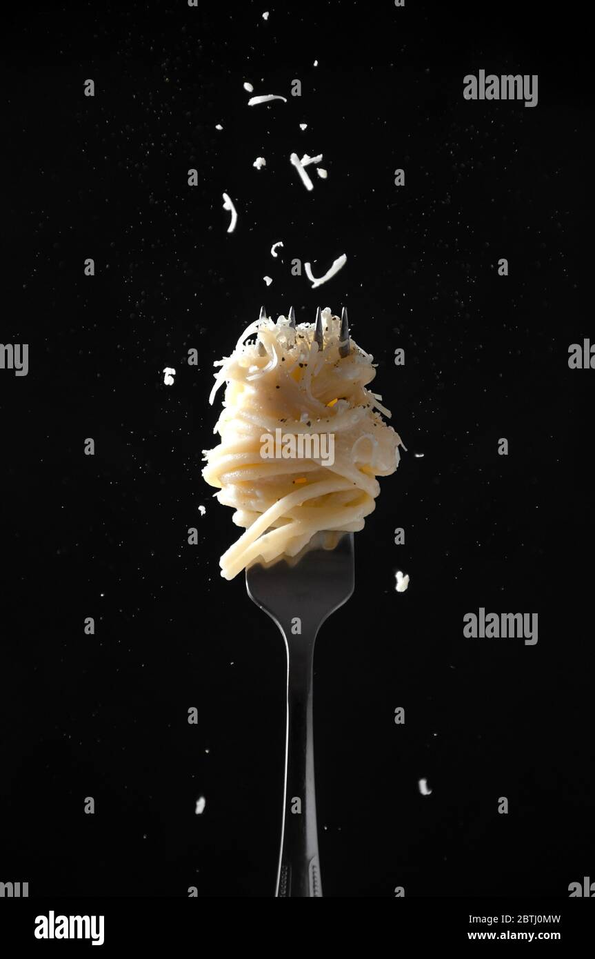 Fork with Spaghetti Sprinkled Cheese and Pepper on Dark Background. Cacio e Pepe - Italian Pasta. Stock Photo