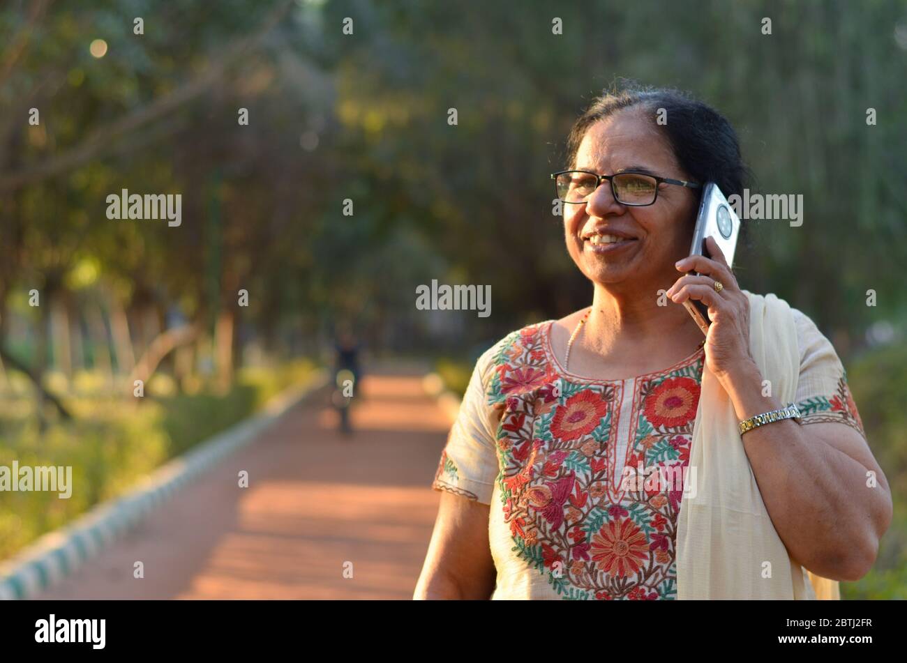 Senior Indian woman laughing and speaking on mobile smart phone in a