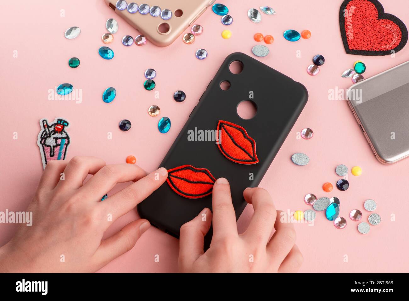 Girl putting red lips patches on black phone case Stock Photo