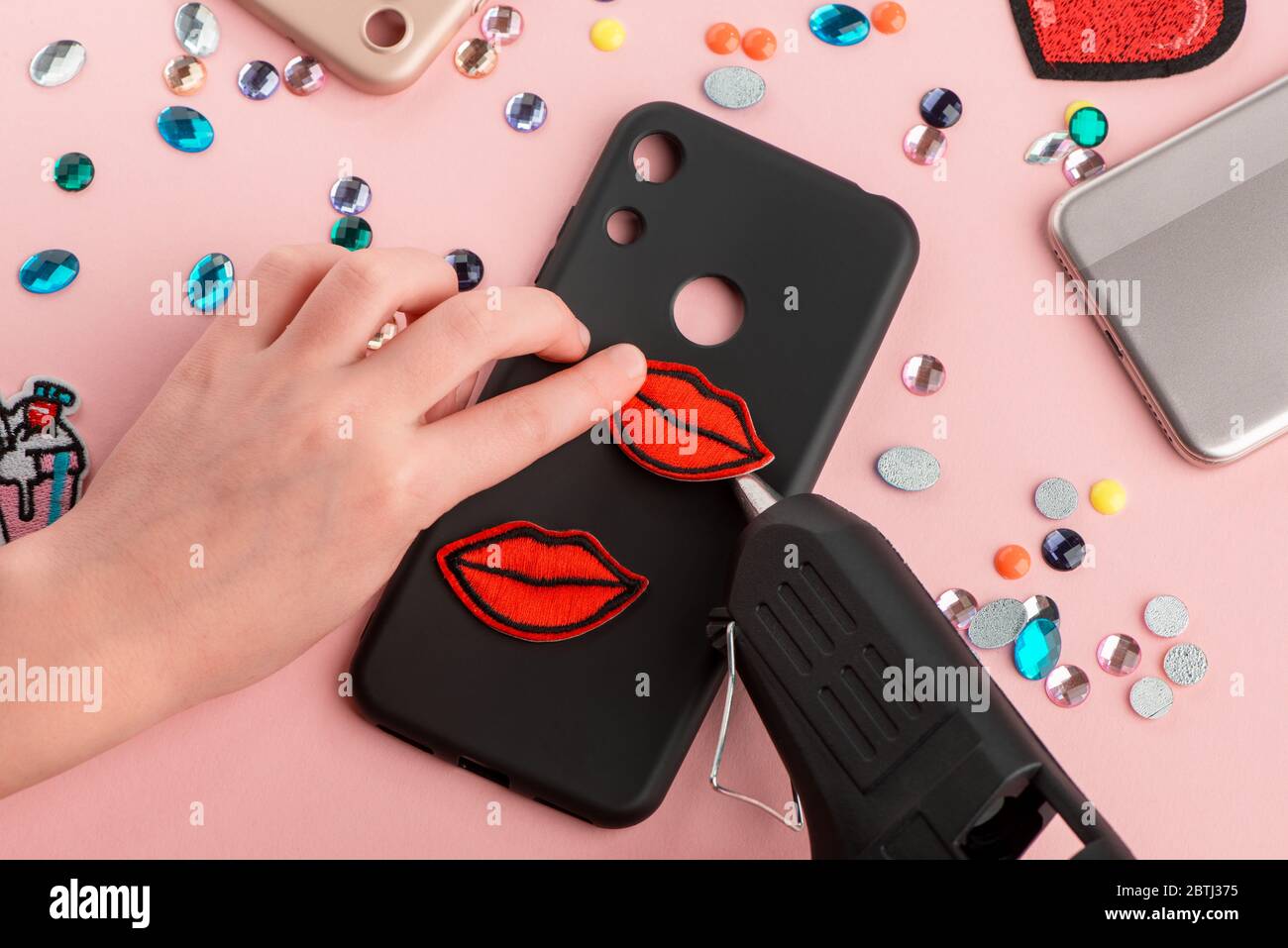 Girl attaching red lips patches onto black phone case Stock Photo