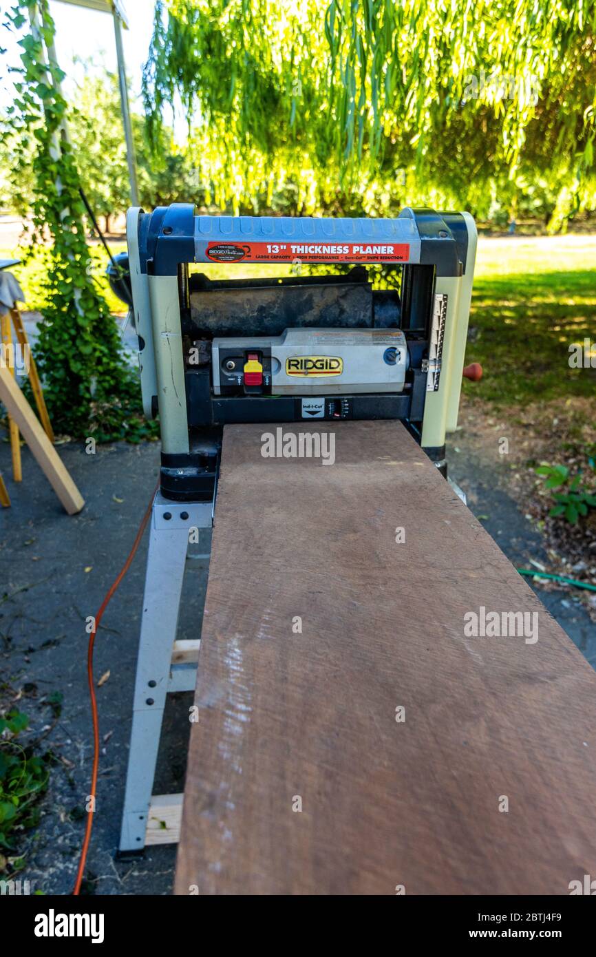 A large rough Black Walnut board being run through a planer in