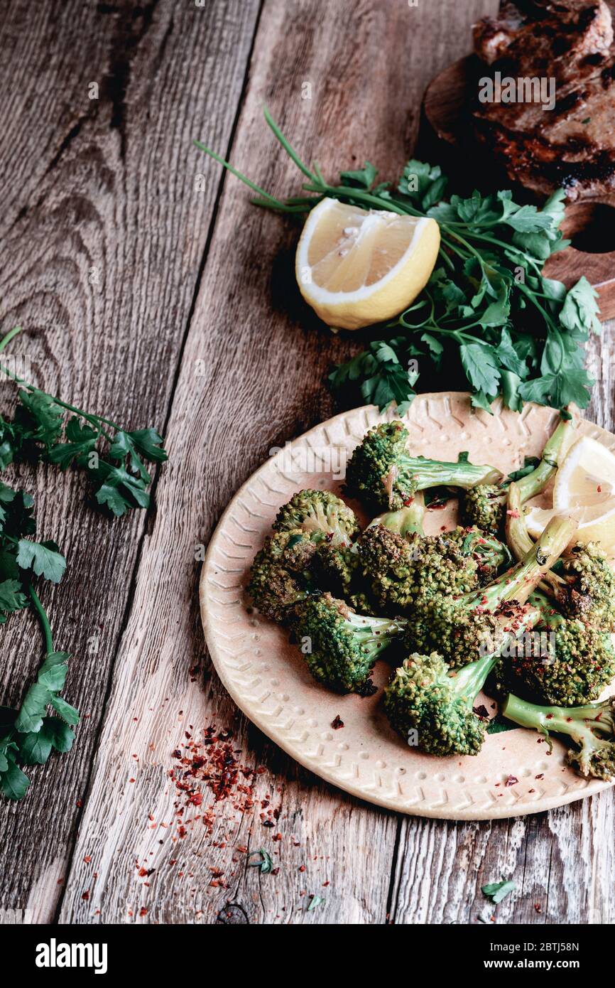 Organic cooked broccolini, herbs and lemon on rustic wooden table, healthy plant based meal Stock Photo