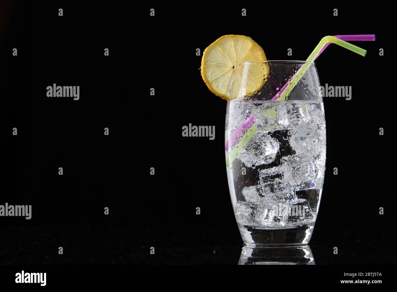 glass of ice water with lemon and straws on black background Stock ...