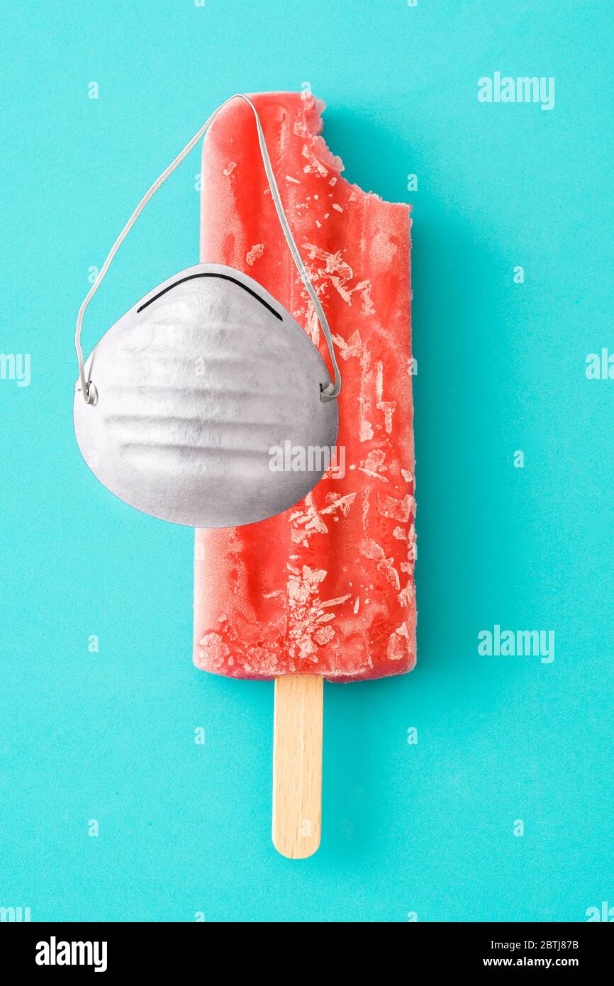 Strawberry popsicles with protective face mask on blue background Stock Photo