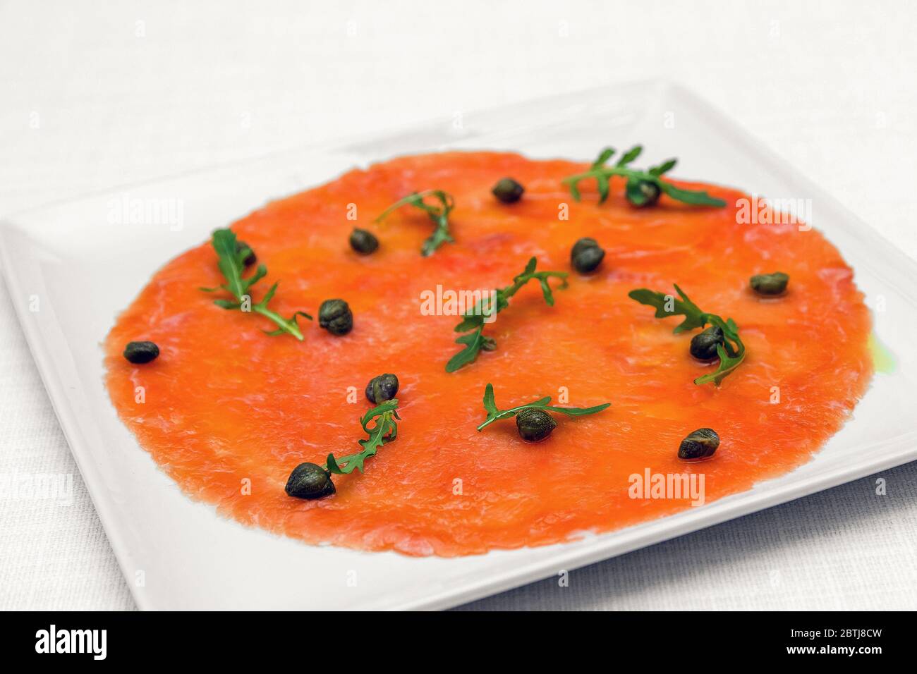 Smoked salmon carpaccio with rocket salad. Restaurant menu. White