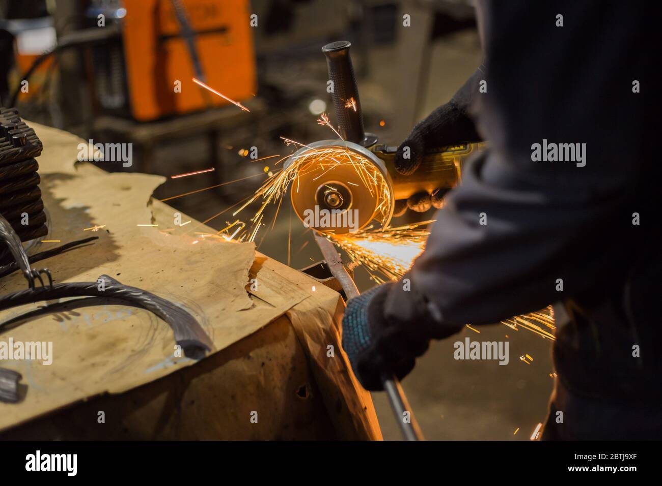 Professional blacksmith sawing metal with hand circular saw at forge ...