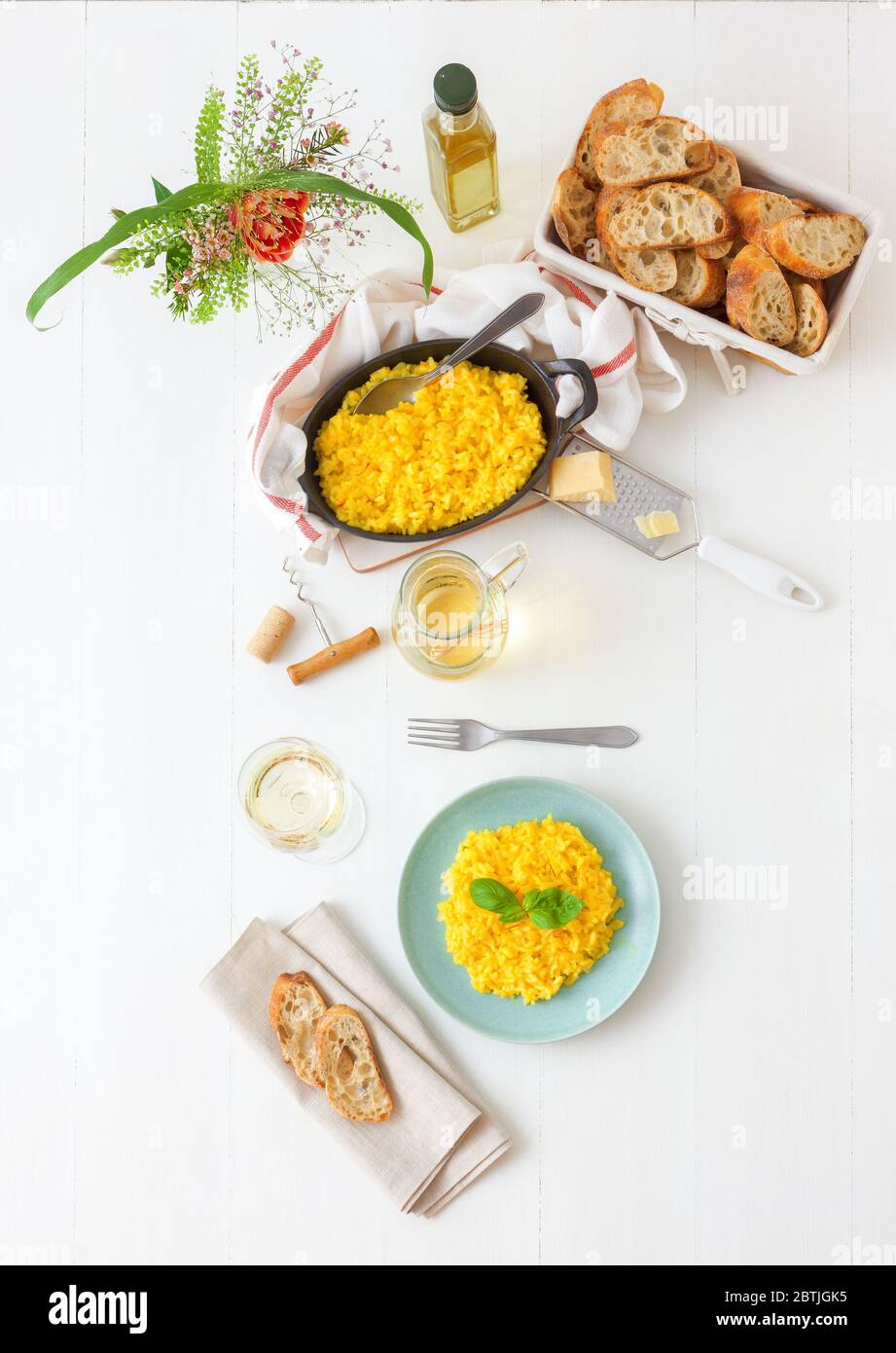 Risotto Milanese, wooden table with traditional Italian saffron risotto, glasses and pitcher of