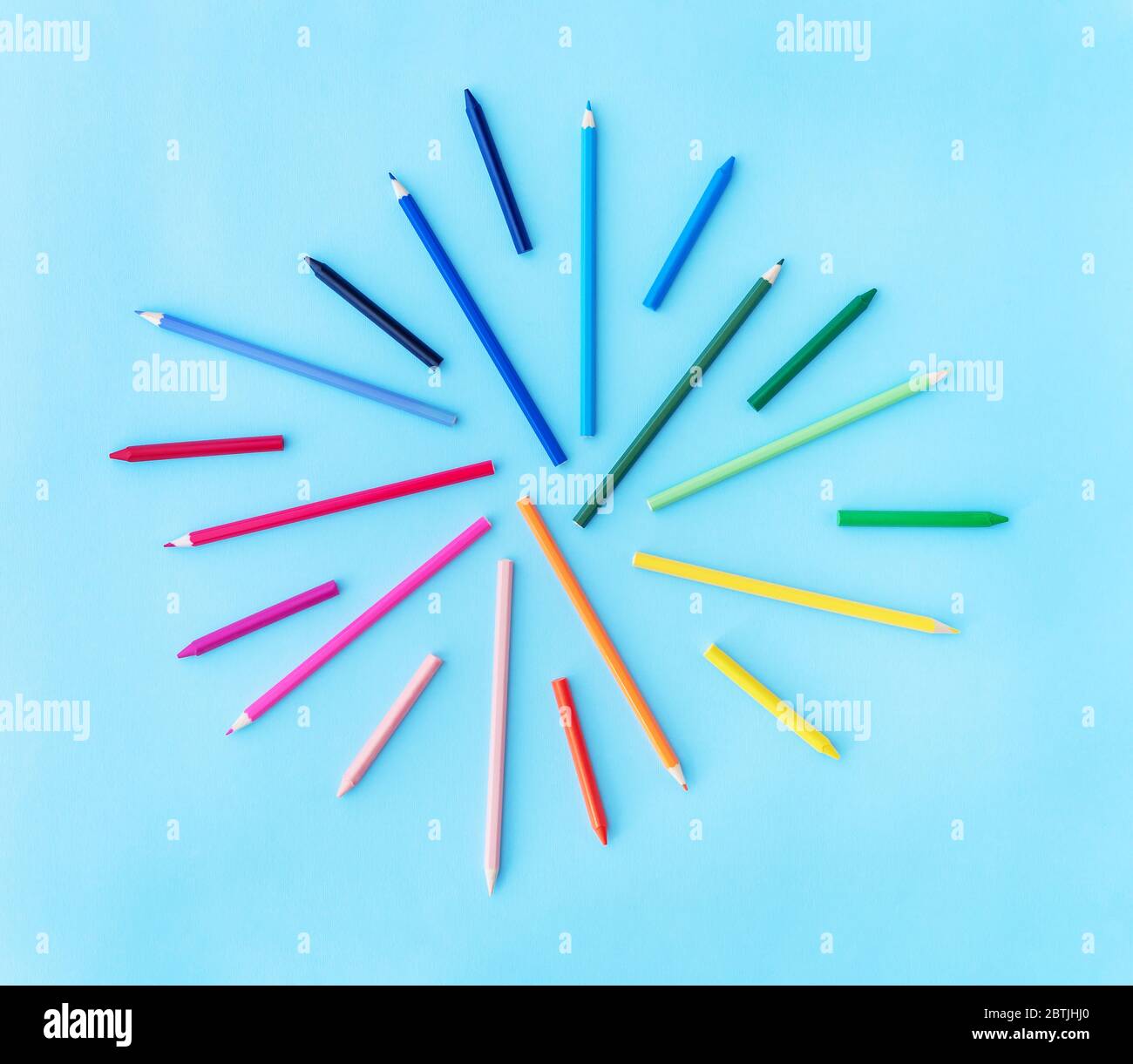 Back to school background with variety of pencils and wax crayons in rainbow colors on pastel blue backdrop. Flat lay style. Place for text. Stock Photo