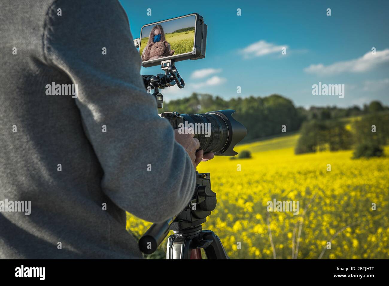 Outdoor Film Making with Digital Camera. Videographer Taking Shots of Caucasian Girl with Scenic Colorful Landscape in the Background. Modern Digital Stock Photo