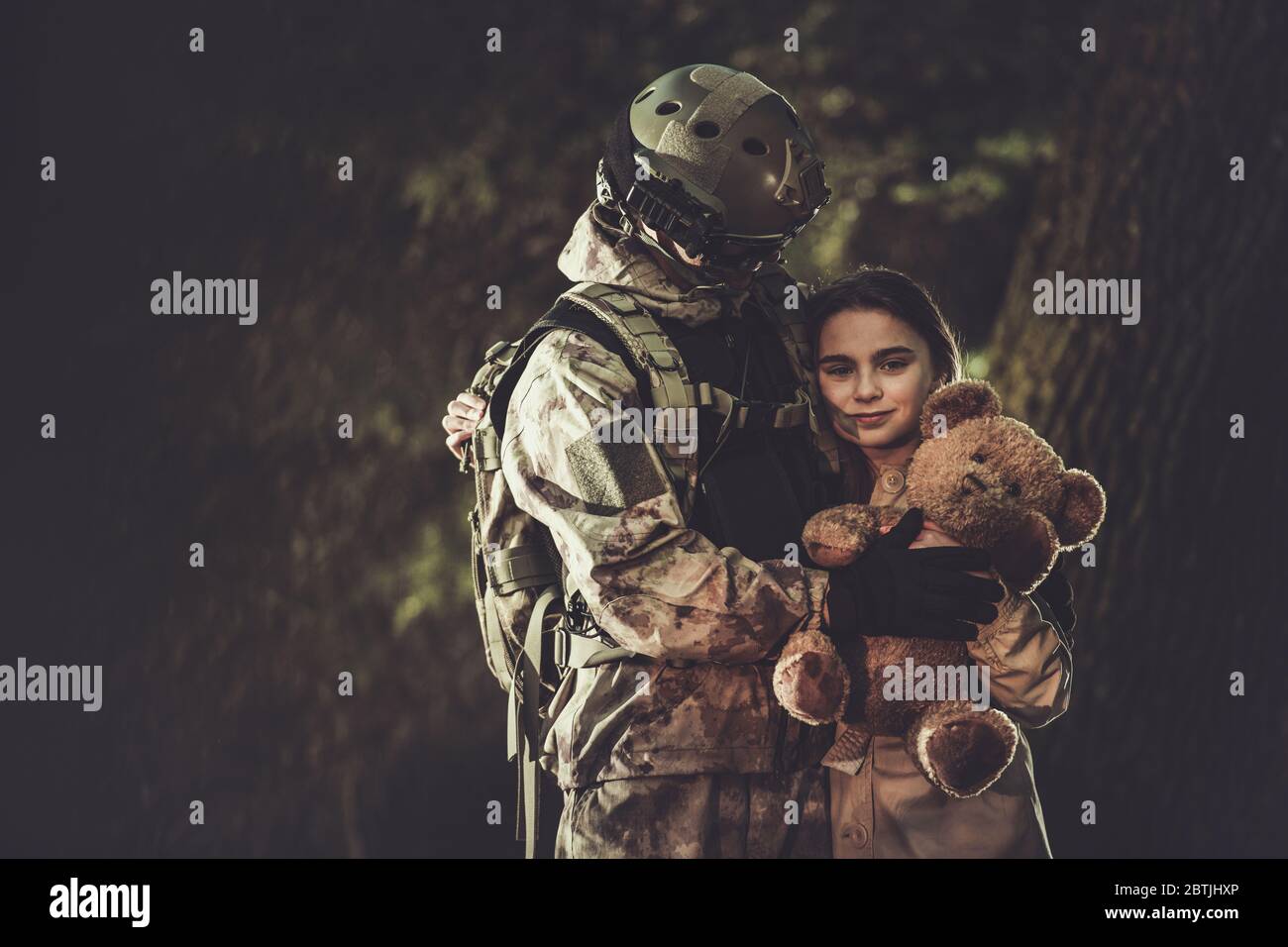 Caucasian Soldier in His 30s in Camouflage Suit Return From Army Mission and Meeting His Daughter. Family Reunited. Girl with Teddy Bear in Hands She Stock Photo
