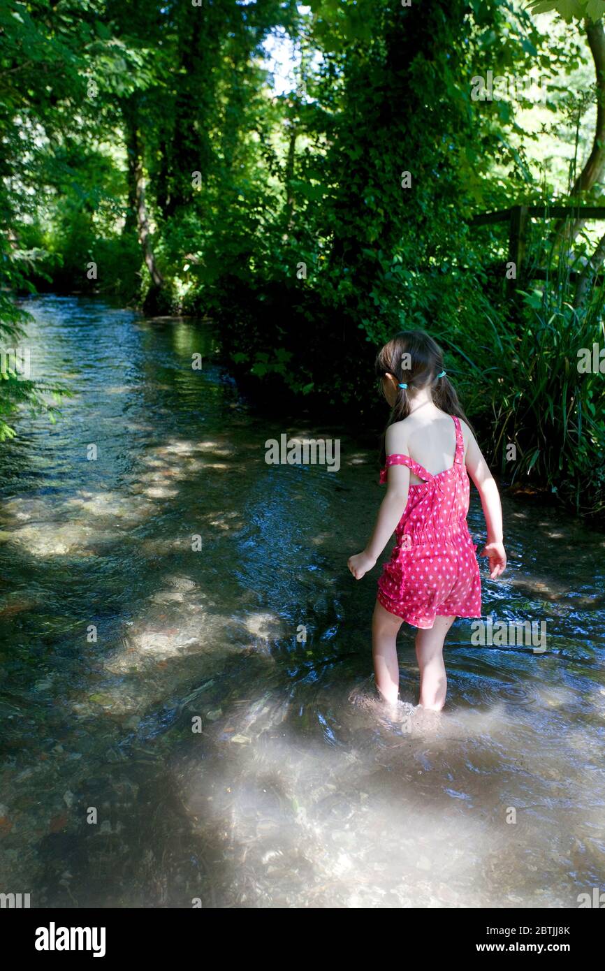 Young girl paddling in fresh water stream, Letcombe Regis, England Stock Photo