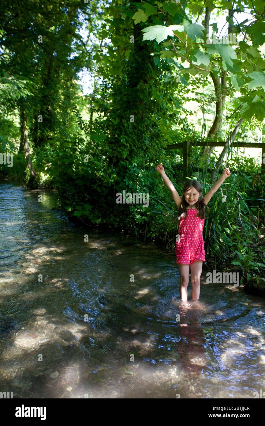 Young girl paddling in a stream, Oxfordshire, England Stock Photo