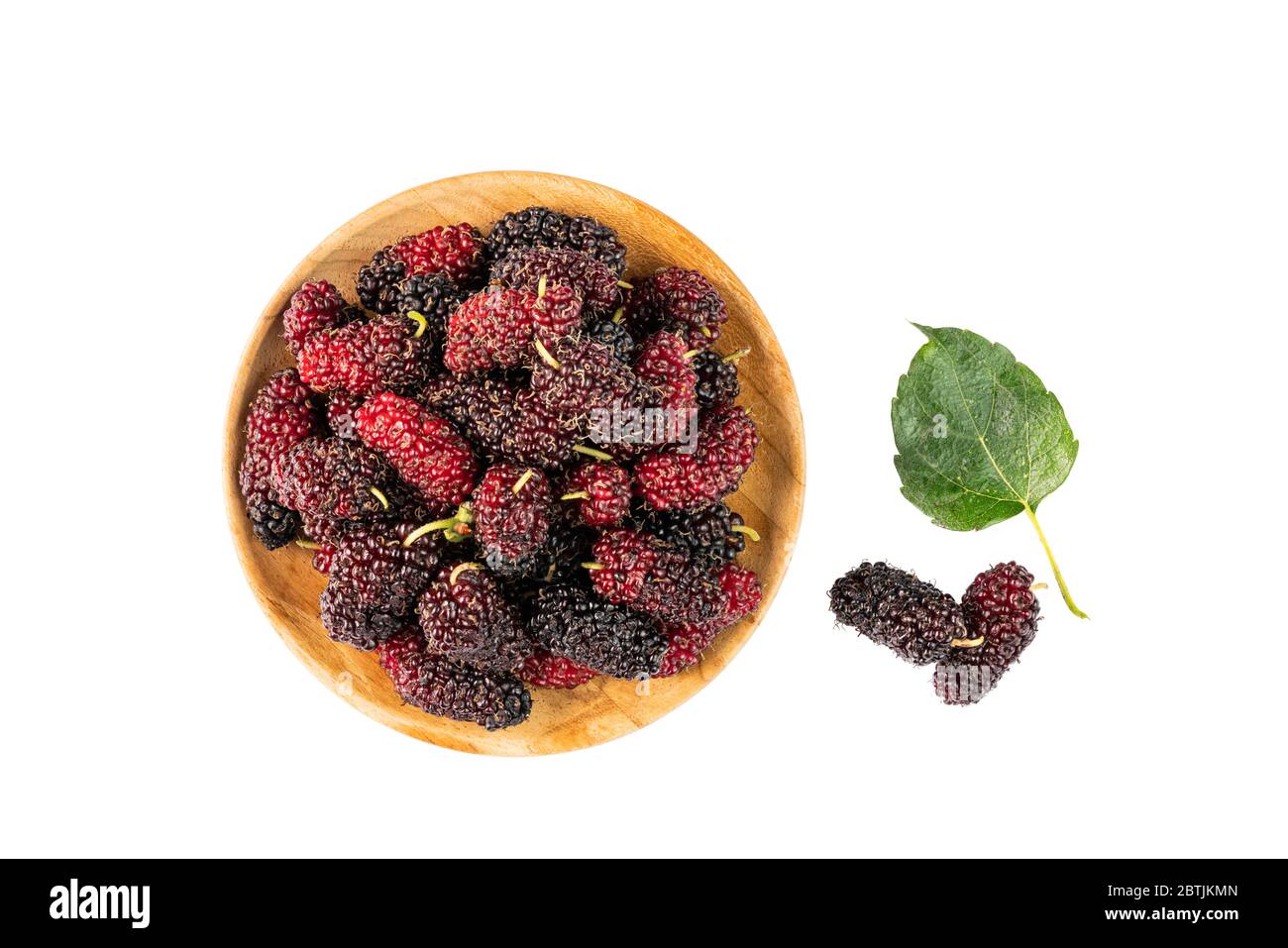 Pile of mulberries in wooden plate and on the floor with leaf on white background with clipping path. Stock Photo