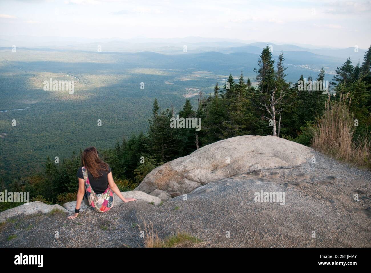 A hiker sitting on a rocky lookout in Mont Megantic National Park near Notre Dame des Bois in Estrie, Appalachia, Eastern Townships, Quebec, Canada. Stock Photo