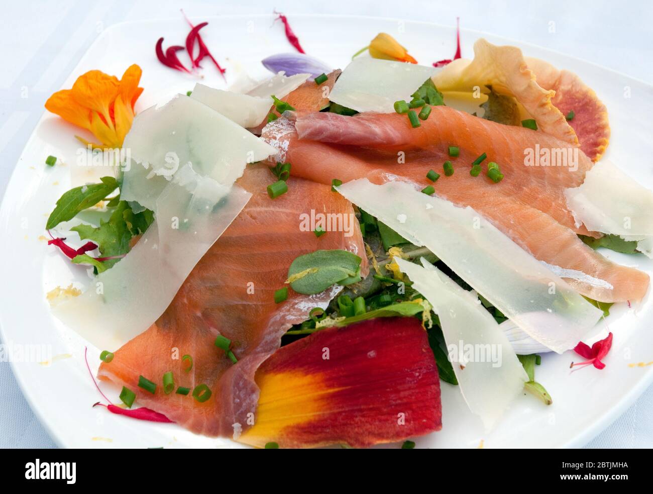 A salad plate with smoked salmon, mixed greens, edible flower petals, parmesan shavings and chives at a B&B in the eastern townships of Quebec, Canada. Stock Photo