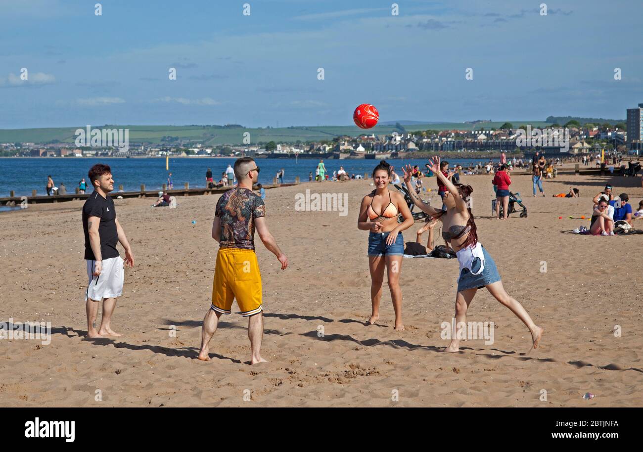 Portobello, Edinburgh, Scotland, UK. 26 May 2020. More relaxed atmosphere at the seaside late afternoon as Scotland nears the end of Phase 1 of Coronavirus Lockdown. Temperature of 19 degrees and sunny. These friends enjoy a volleyball game. Stock Photo