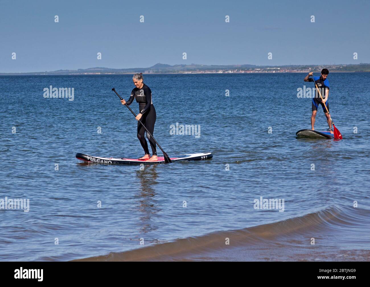 Portobello, Edinburgh, Scotland, UK. 26 May 2020. More relaxed atmosphere at the seaside late afternoon as Scotland nears the end of Phase 1 of Coronavirus Lockdown. Temperature of 19 degrees and sunny. Pictured the Harrison family, mum and her sons enjoy stand up paddle boarding. Stock Photo