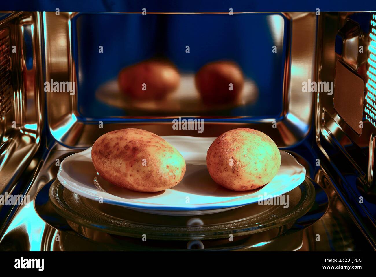 Two baked potatoes ready to cook in a microwave oven Stock Photo