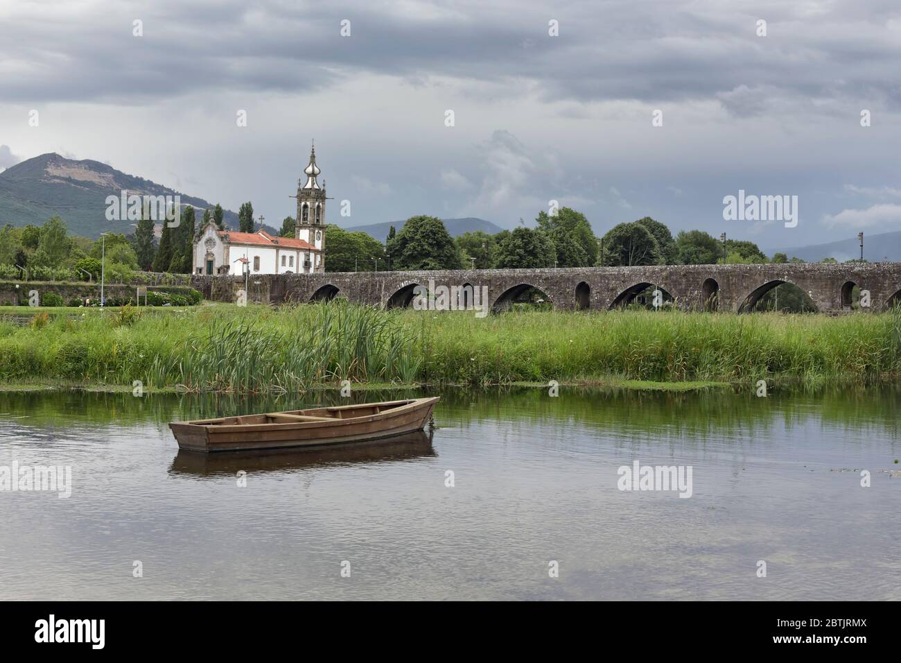 Old granite bridge and church from the medieval city of Ponte de Lima in a rainy day; north of Portugal Stock Photo