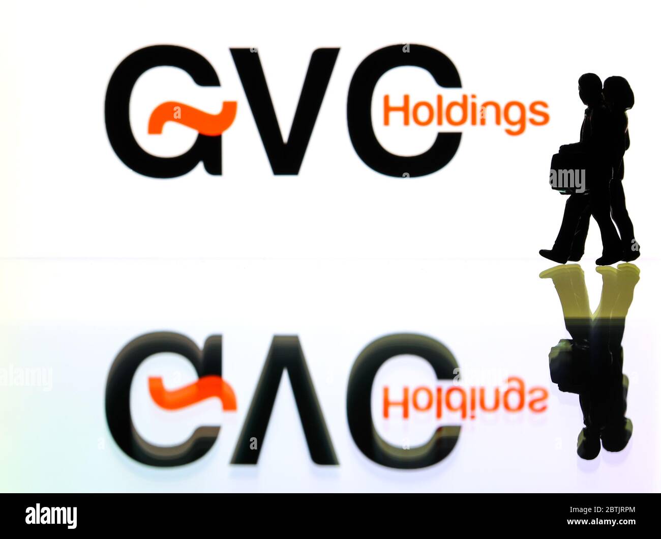 silhouettes in front of the logo for GVC Holdings the British sports betting company. (editorial use only) Stock Photo