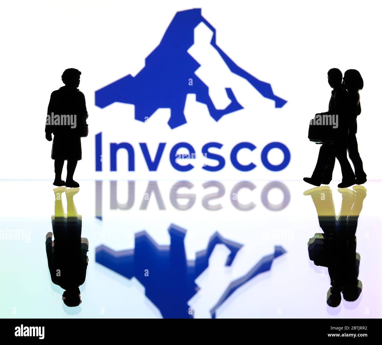 silhouettes in front of the logo of Invesco investment management company (editorial use only) Stock Photo