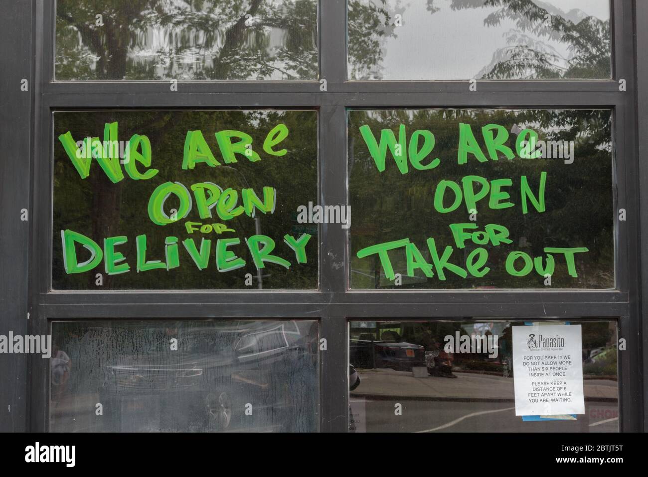 a painted restaurant window stating we are open for delivery and we are open for take out in bright green during the coronavirus or covid-19 pandemic Stock Photo