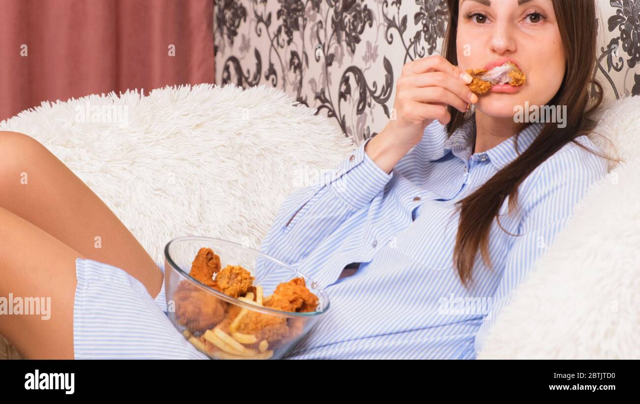 Young happy woman eating deep fried chicken, closeup. Woman eats