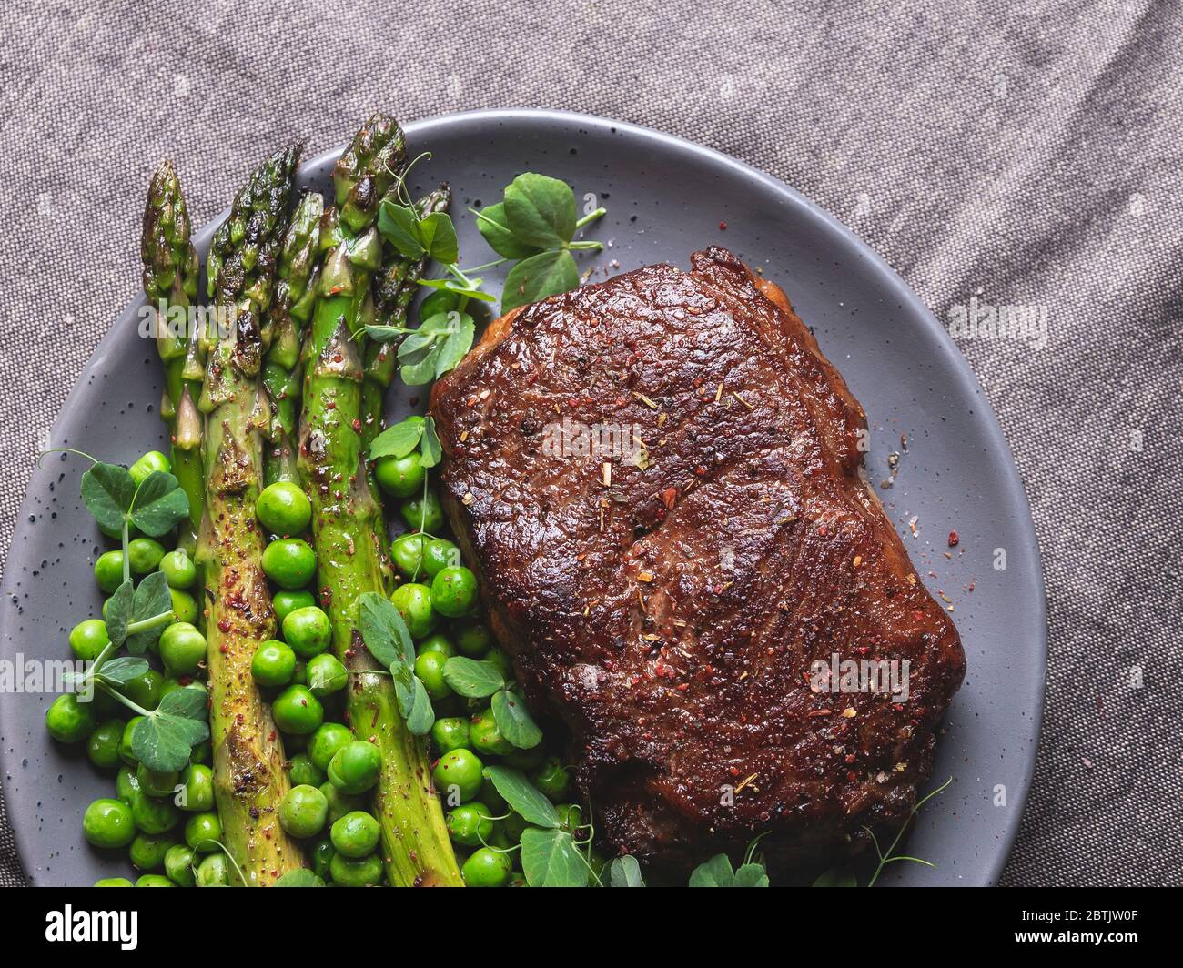 juicy roasted beef steak, mutton with asparagus green peas on a plate, close up Stock Photo