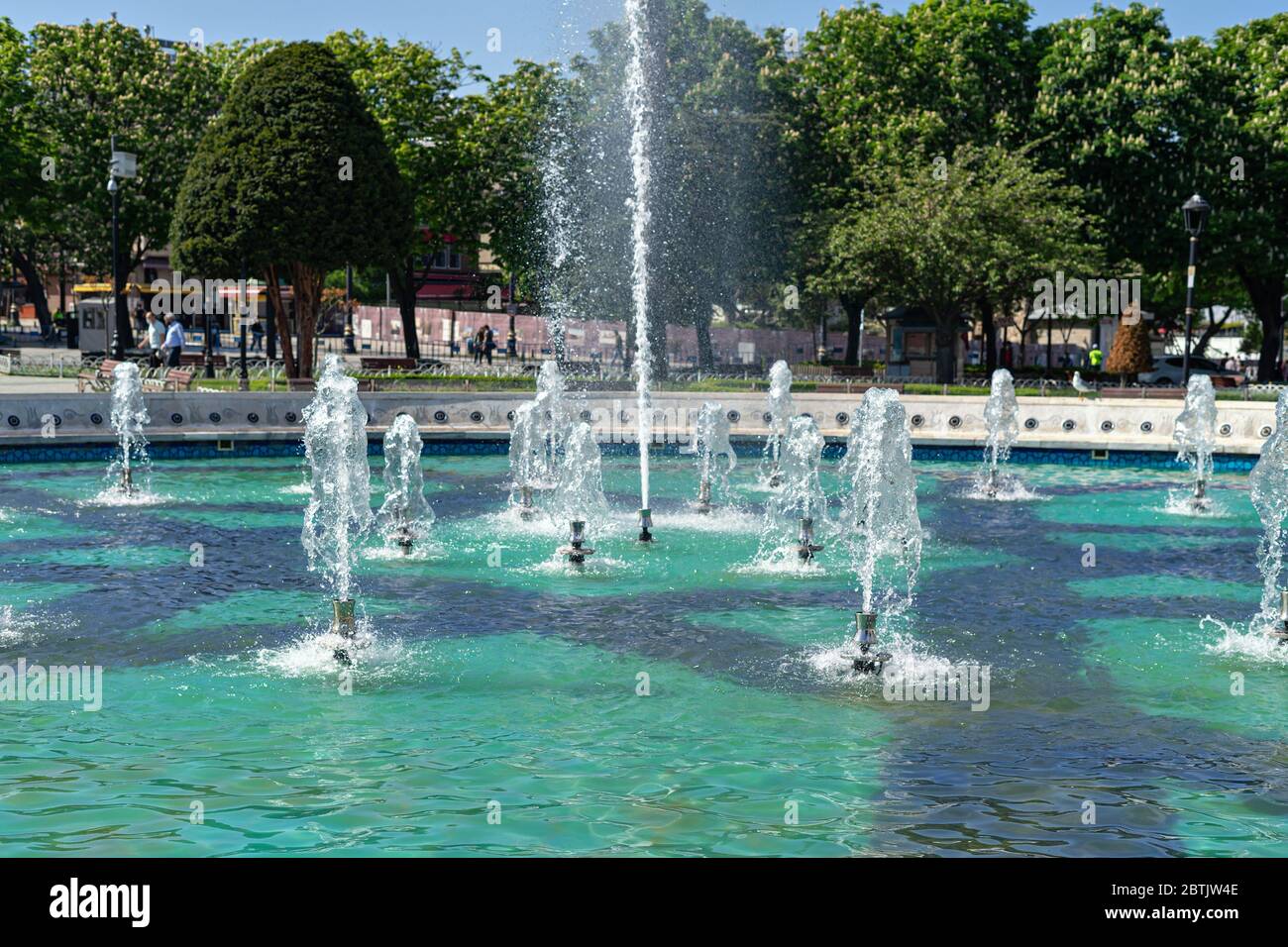 Fountain in city park with green trees at sunny day Stock Photo - Alamy