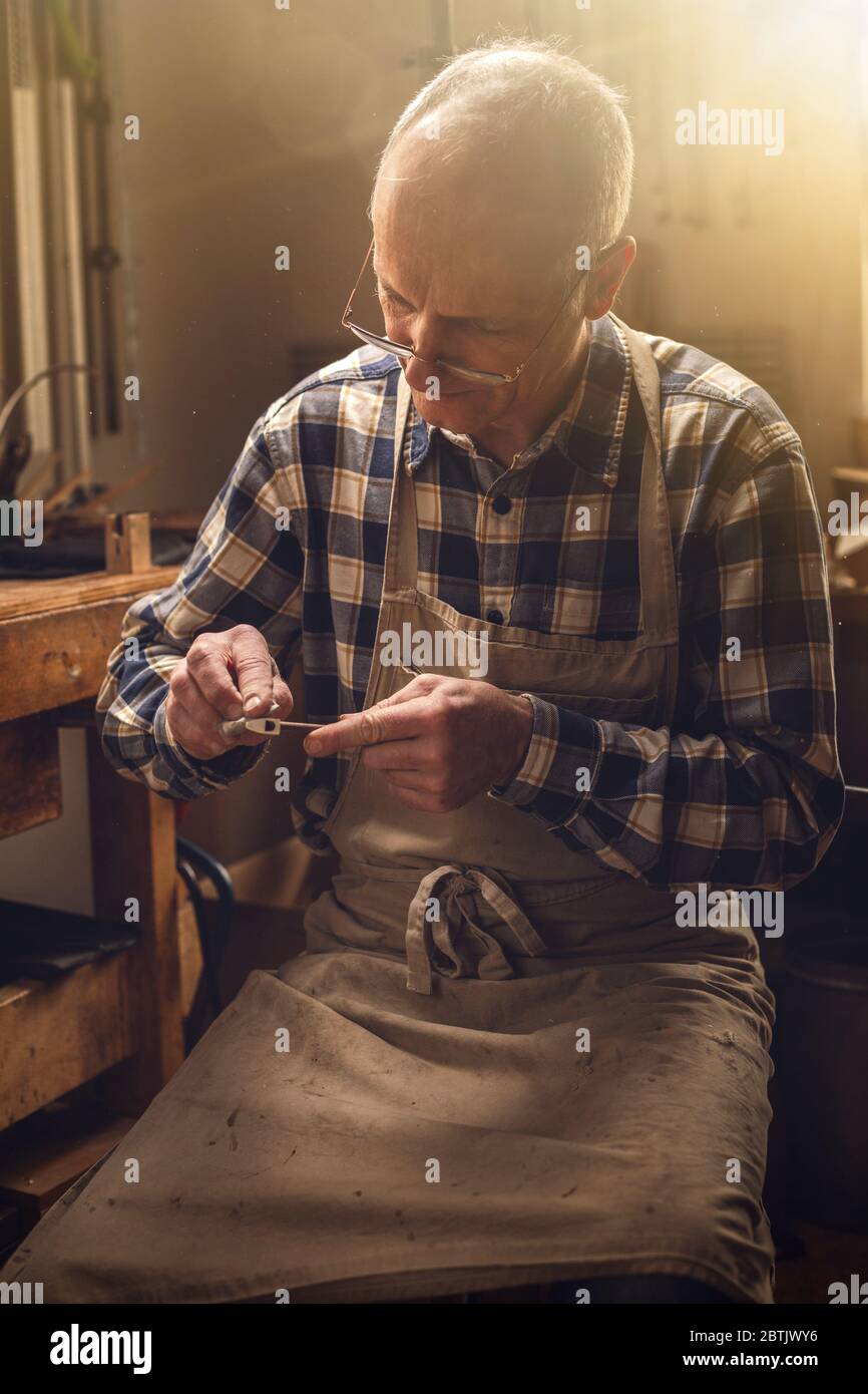 Mature carpenter working on a violin bow Stock Photo