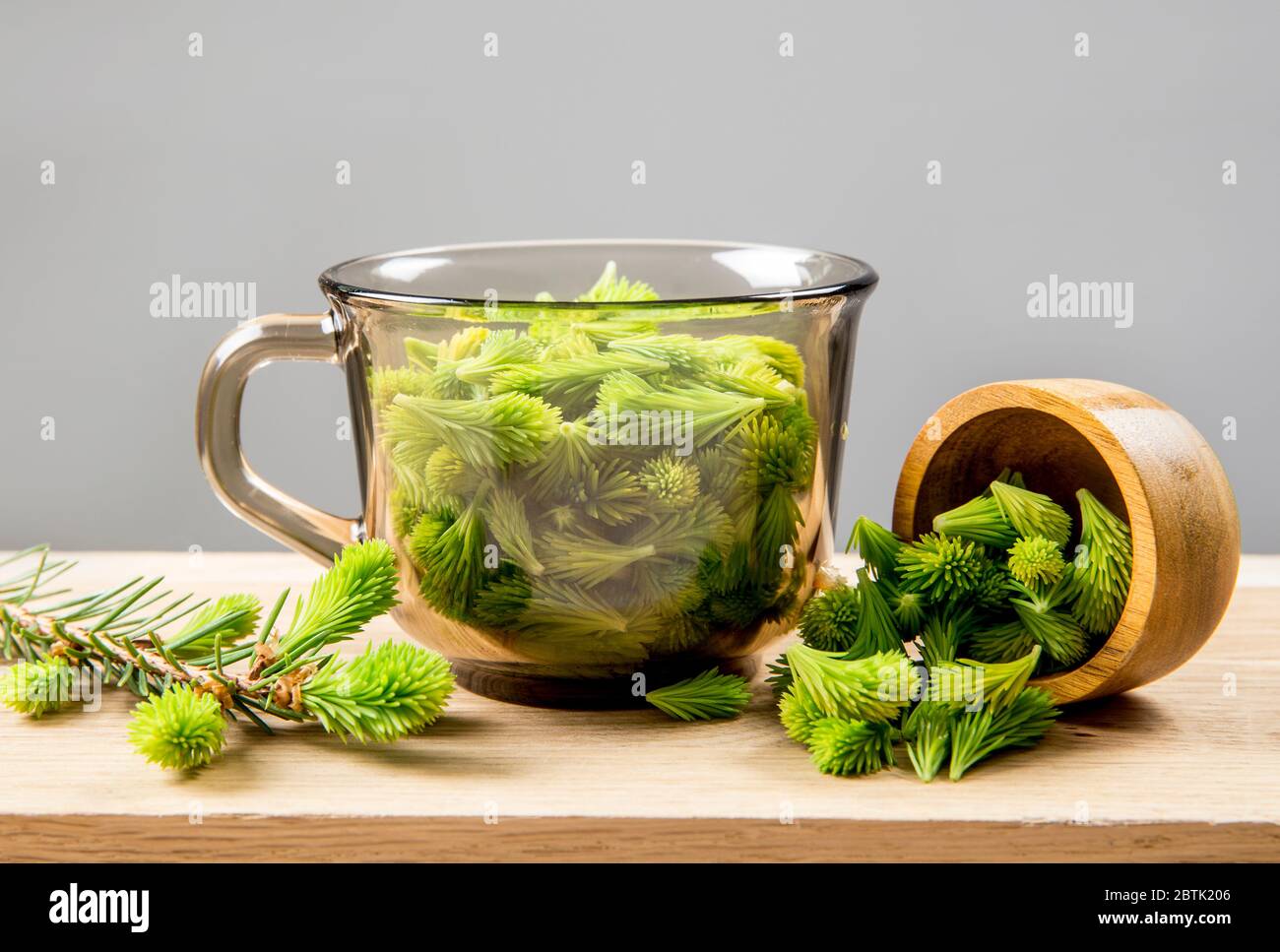 Conceptual image of using fresh young spruce tree (Picea abies) shoots for food and drink. Clear glass cup full of green soft spruce shoots. Alternati Stock Photo