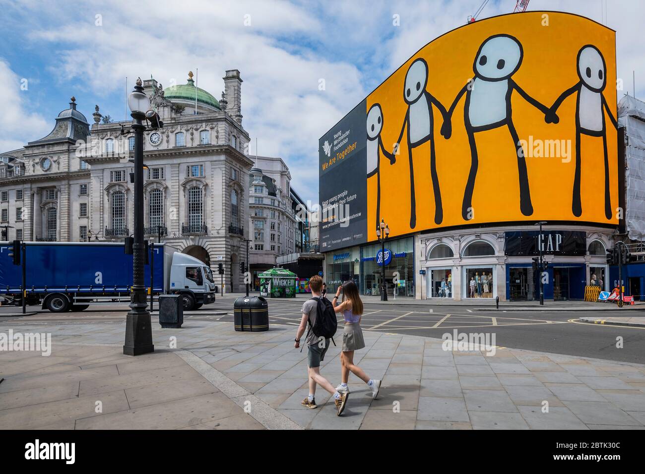 London, UK. 26th May, 2020. A new artwork entitled We Are Together by STIK was unveiled on London's 783 square metre Piccadilly Lights, the largest screen in Europe, as part of Young Westminster Foundation's (YWF)'s new flagship campaign to support young people during the coronavirus. STIK's figures rotate around the curved screen portraying young people living in the heart of London, holding hands as a beacon of hope and connectedness with the rest of the world. The 'lockdown' continues for the Coronavirus (Covid 19) outbreak in London. Credit: Guy Bell/Alamy Live News Stock Photo