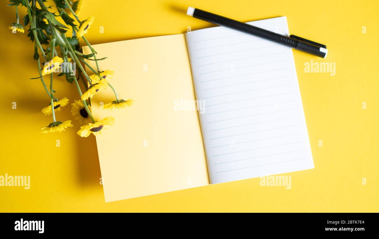 Blank open Notepad. Bright and yellow notebook for girls with flowers. Business and copy space concept. Top view Stock Photo