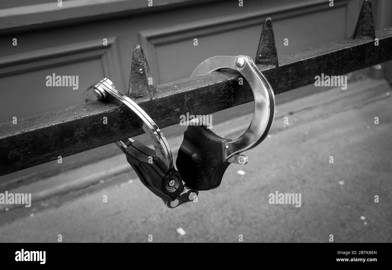 Police handcuffs closed over a metal railing. Black and white photo. Stock Photo
