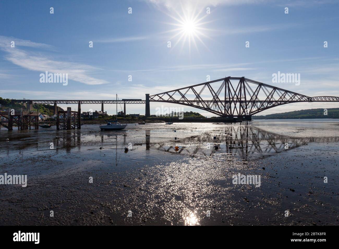 Scotrail class 158  train at North Queensferry, The Forth Bridge (Fife) with the bridge reflected in the wet river bank Stock Photo