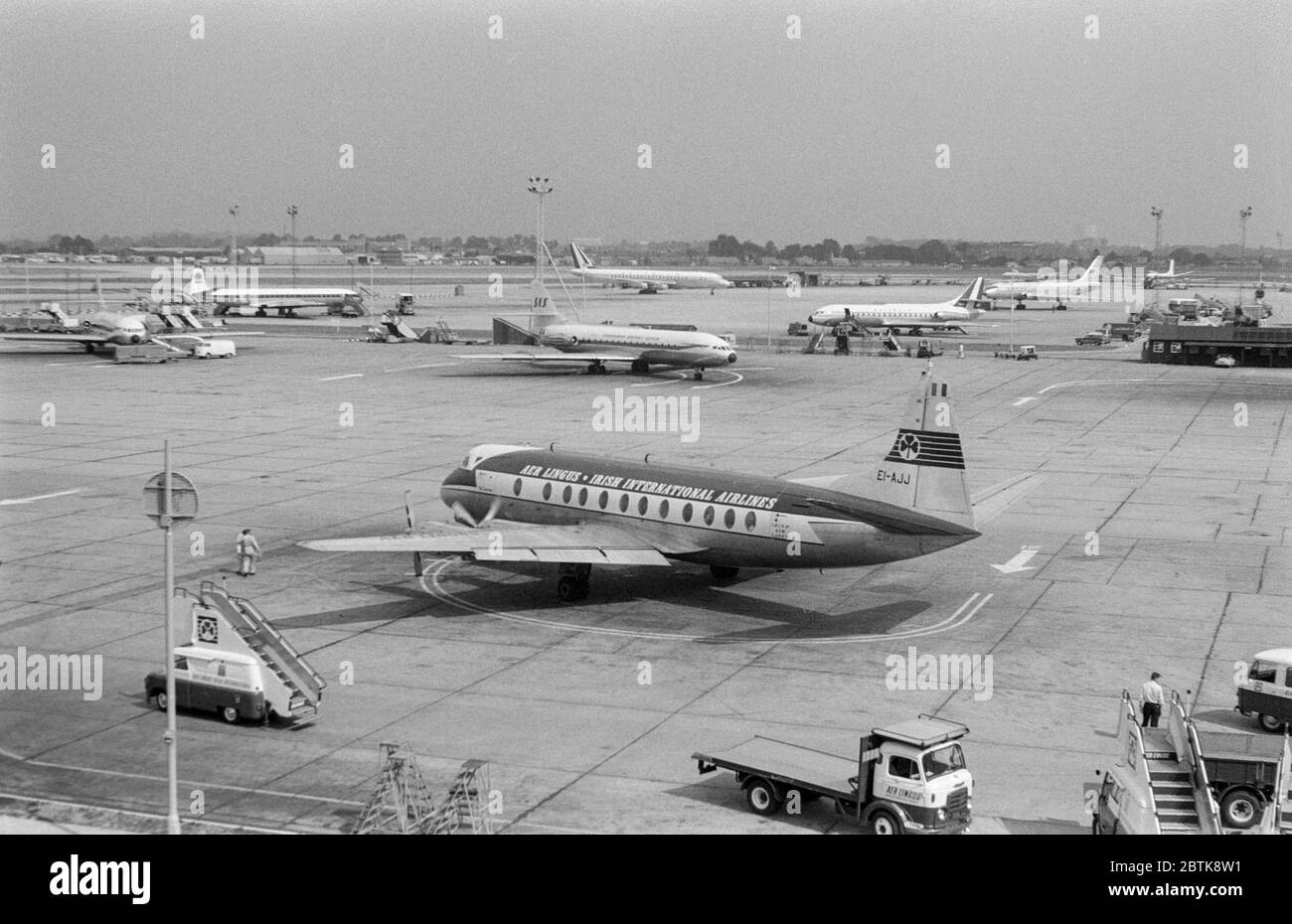 Vintage early 1960s black and white photograph showing aircraft at London Heathrow Airport. In the foreground is an Aer Lingus Vickers Viscount, registration EI-AJJ. Various Jet airliners in the background. Stock Photo