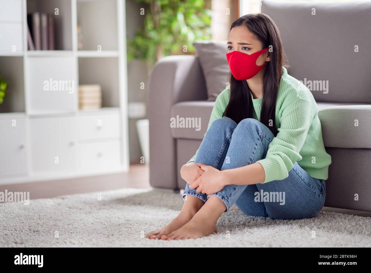 Photo of domestic sad corona virus sick patient asian lady sit floor carpet couch hold legs knees suffering infection illness self isolation social Stock Photo