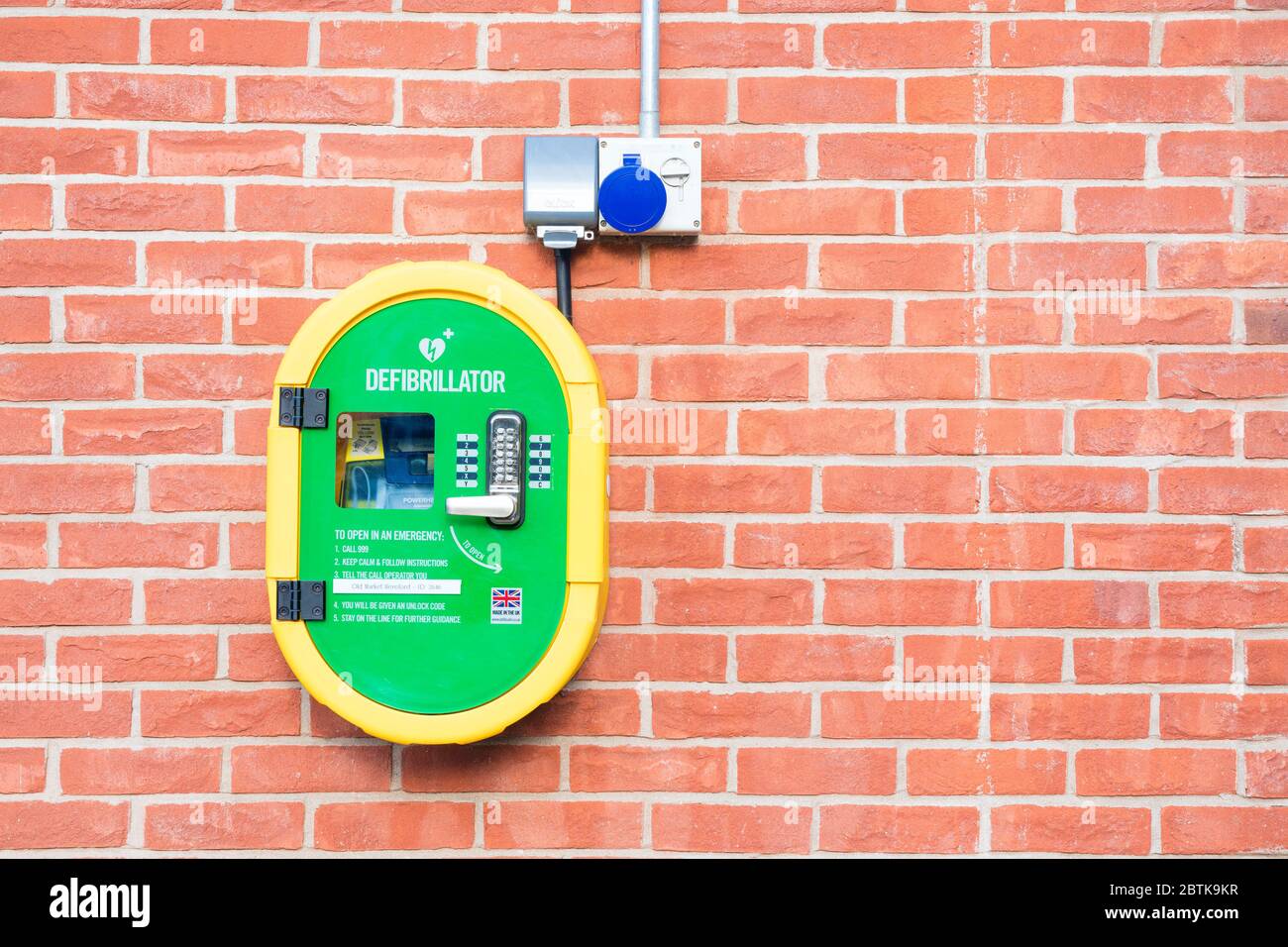 Defibrillator on a brick wall, UK. Stock Photo