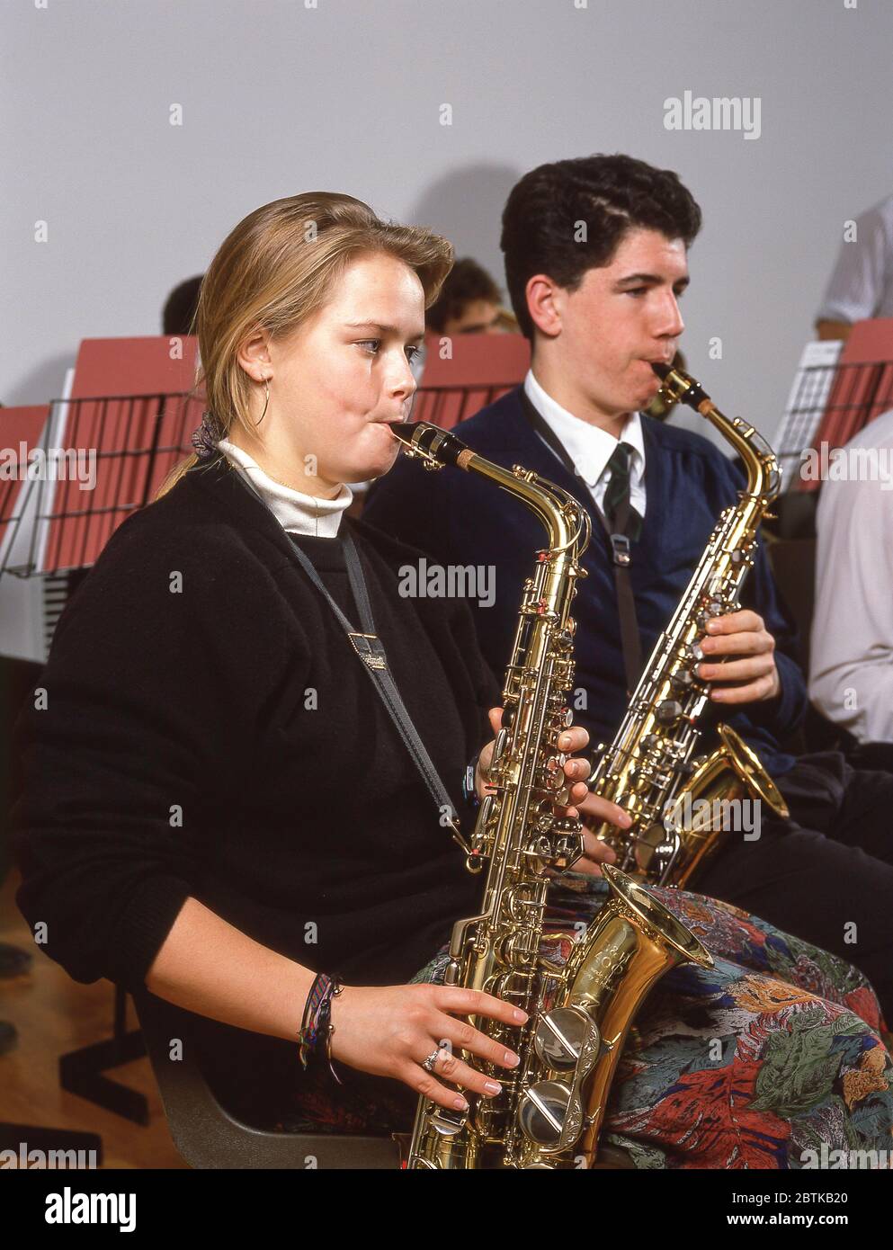 Couple playing saxophone in school orchestra, Surrey, England, United Kingdom Stock Photo