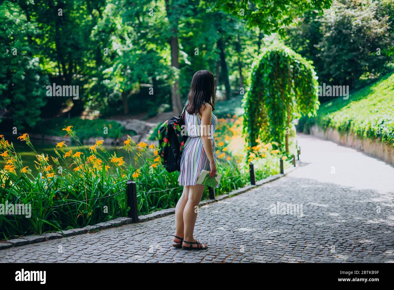 Sofia Park, Uman. Young woman with a backpack walking in the park. Girl in a sundress and a tourist map on the trail in the park. Tourist with a backp Stock Photo