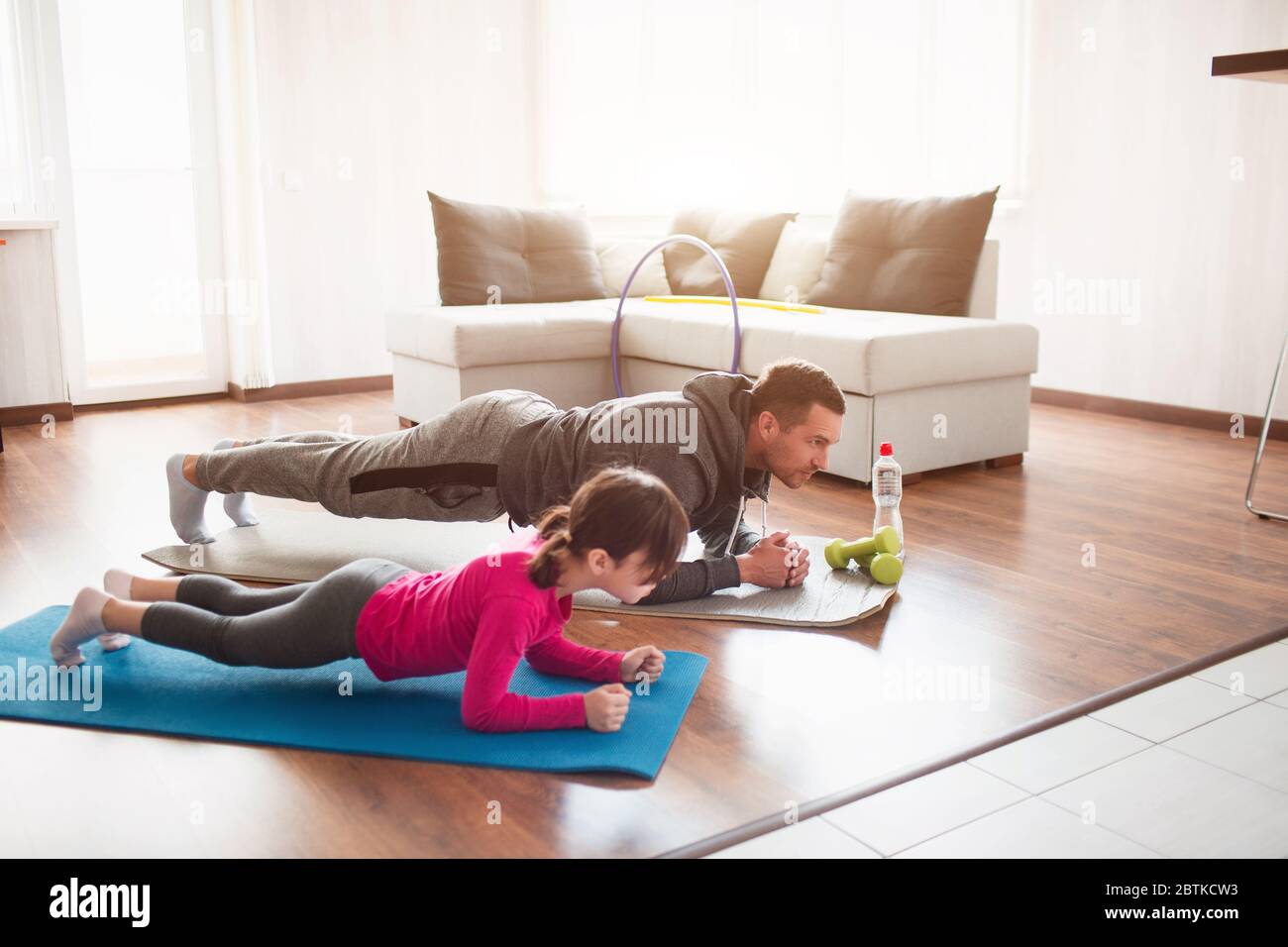father and daughter are training at home. Workout in the apartment. Sports in home conditions. They make the doing plank Stock Photo