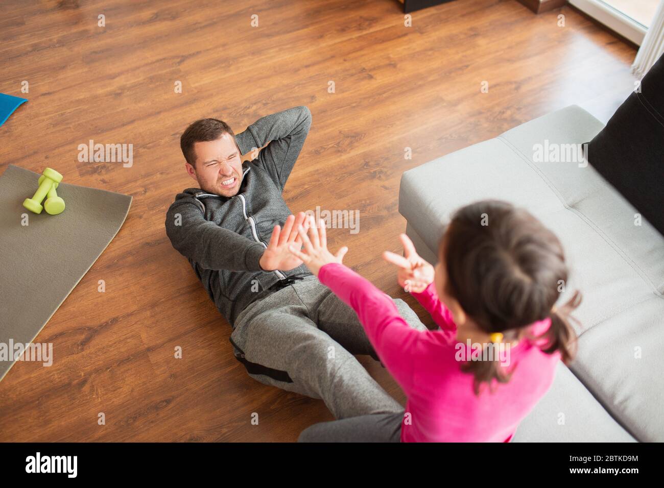 father and daughter are doing abs training at home. Workout in the apartment. Sports training in the living room. Stock Photo