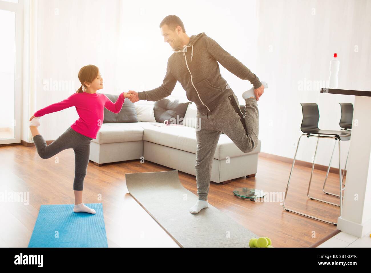 father and daughter are training at home. Workout in the apartment. Sports at home. They do exercises with yoga or Pilates Stock Photo