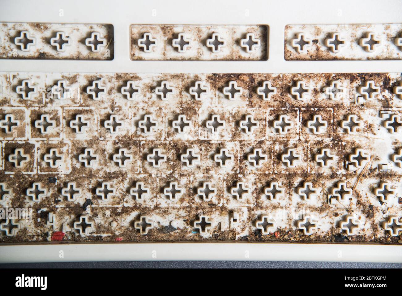 Dirty stain under the keypad of keyboard computer, unsightly and unclean equipment in office. Stock Photo