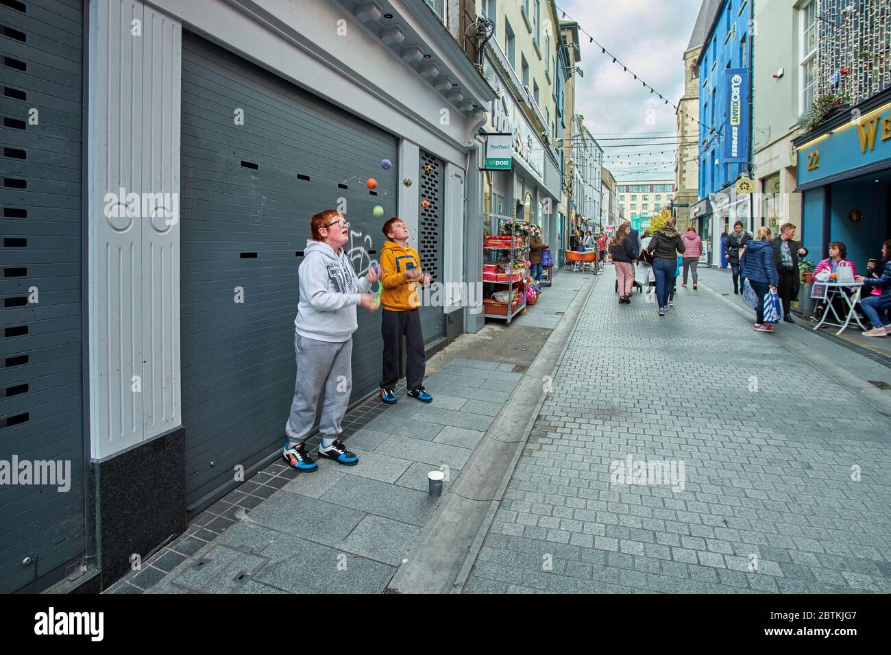 Two young Irish lads youths are busking by juggling on a street in Wexford Ireland. Boy jugglers. Stock Photo