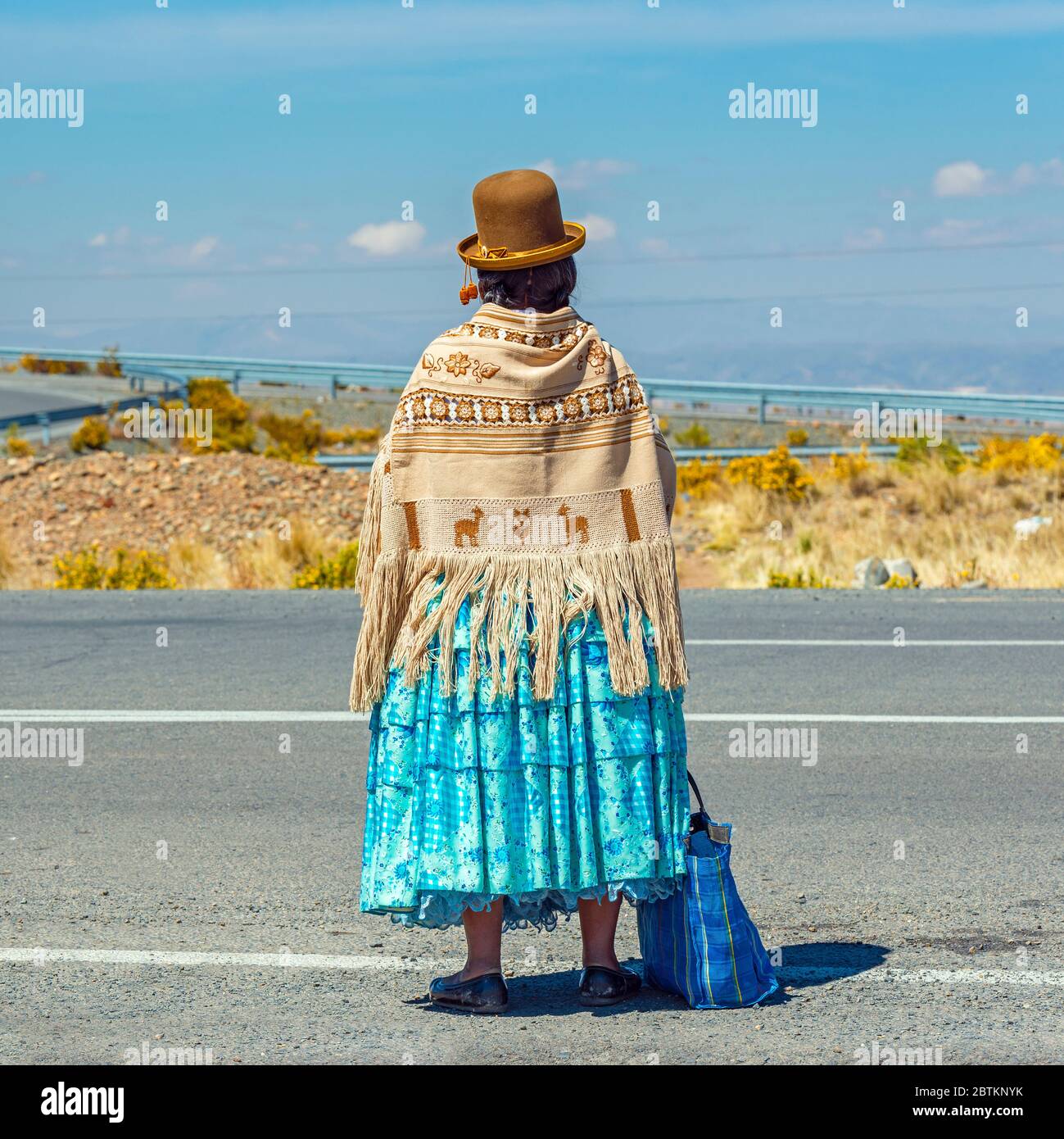 Bolivian Aymara Indigenous woman waiting for transport along a highway, La Paz, Bolivia. Stock Photo