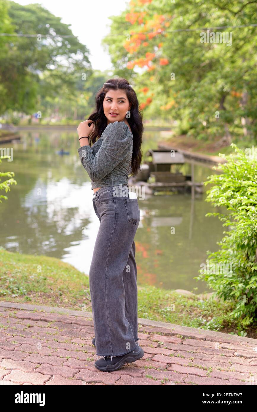 Full body shot of happy young beautiful Indian woman looking back at ...