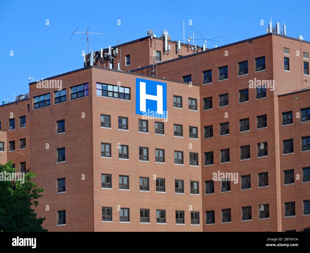 large brick hospital type building with block letter H sign Stock Photo