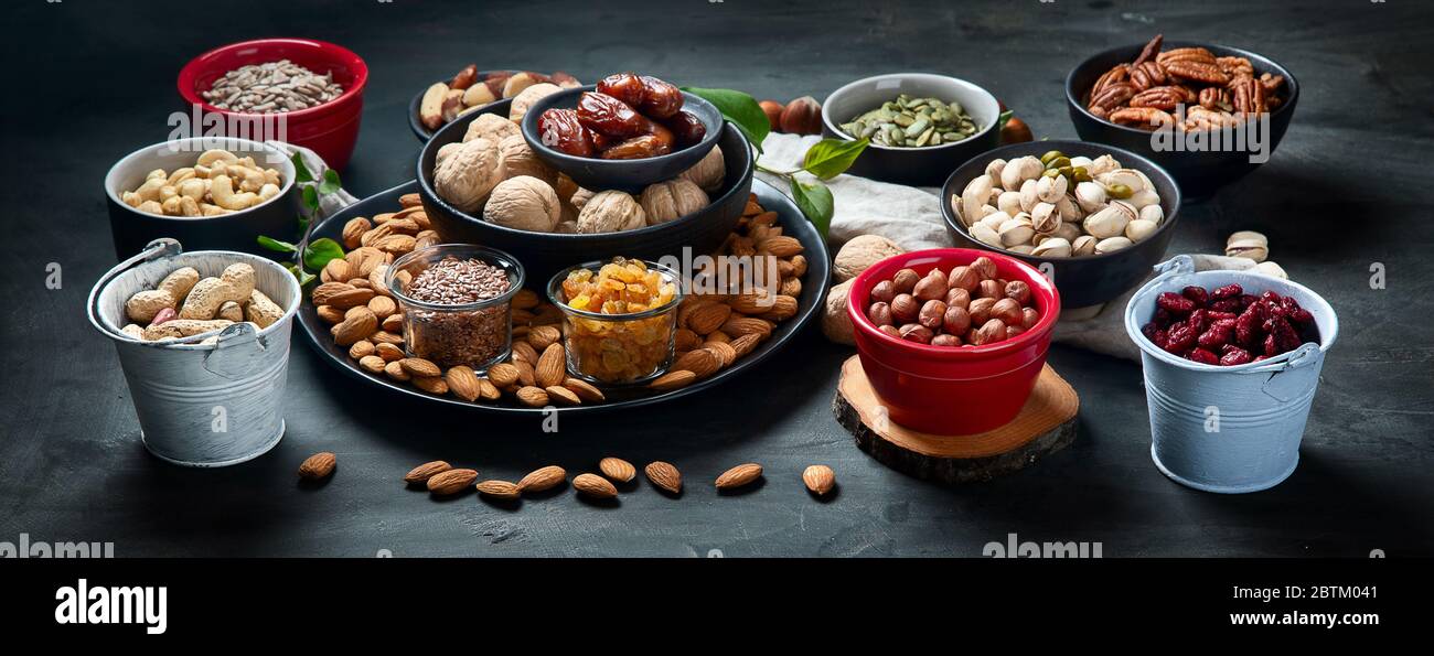 Different types of nuts, seeds and dried fruits on black background